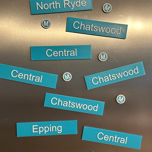 Turquoise 3D printed Sydney Metro station-sign fridge magnets on a fridge door