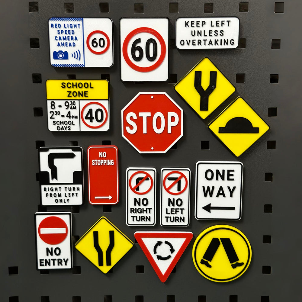 Full set of 3D printed Australian road-sign fridge magnets including Stop, School Zone, Roundabout and speed-limit signs on a pegboard